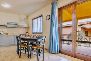 Un comedor con mesa y sillas, una cocina con armarios y estufa, y vista a un edificio a través de una ventana.