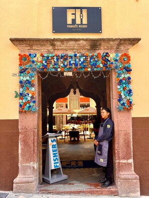 The entrance of Fisher's House Hotel with a colorful floral archway and a signboard displaying the hotel's name. - Fishers House Hotel San Miguel (San Miguel de Allende)