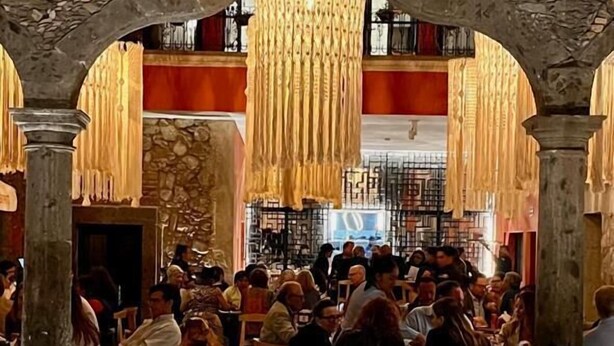 A crowded restaurant with stone arches and hanging chandeliers. - Fishers House Hotel San Miguel (San Miguel de Allende)