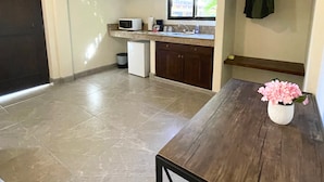 A compact kitchen with a microwave, sink, and window. A small refrigerator is visible, and a potted plant is on a table. - Posada Don Esteban by PartnerHost (Loreto)
