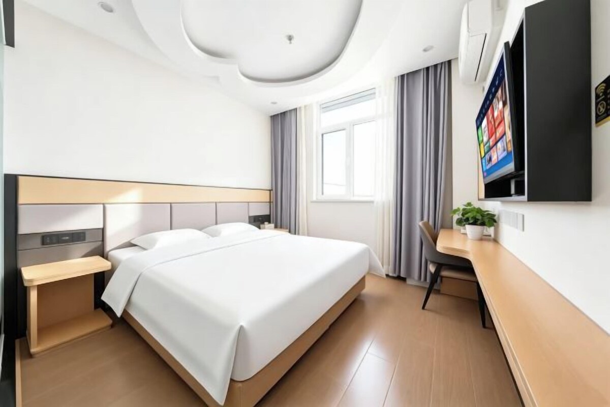 A modern hotel room with a large bed, bedside tables, a desk, and a television.