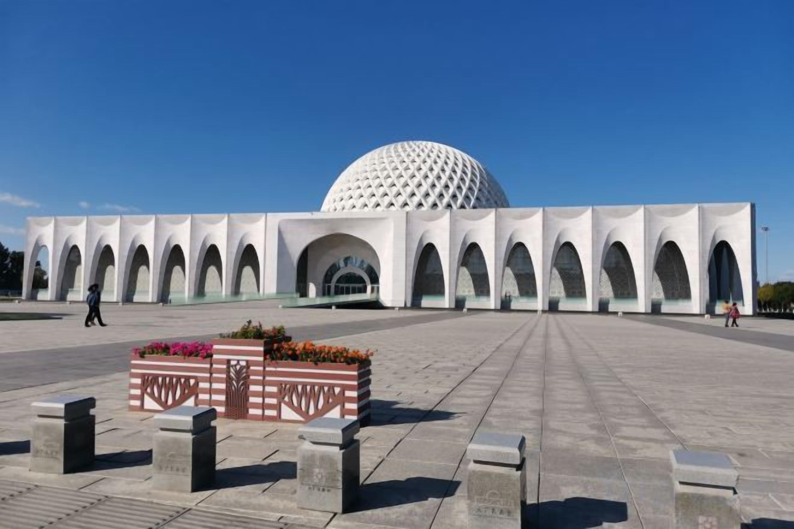 A large, white, dome-shaped building with a series of arches in front.