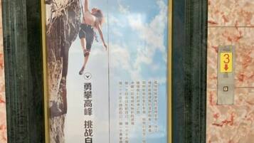 Un cartel vertical con una persona escalando una roca, un número de teléfono y un indicador de planta.