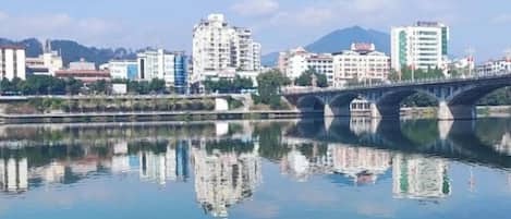 A calm river with a bridge and buildings in the background.