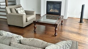 Un salon avec une cheminée, un canapé, une table basse et un téléviseur fixé au-dessus de la cheminée.