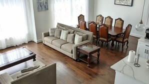 Un salon comprenant un canapé, une table basse, une table à manger avec des chaises, ainsi qu’un coin cuisine avec un comptoir et des placards.