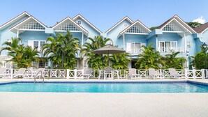 A resort with a swimming pool, white lounge chairs, and palm trees. - 🏝️ Sleep to Caribbean Waves Pool | Beach + Pool + AC • Ocho Rio (Ocho Rios)
