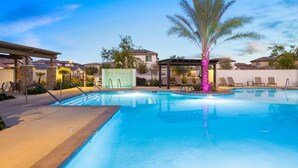 A swimming pool with a palm tree, lounge chairs, and a covered area with a pergola.