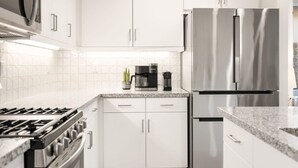 A modern kitchen with white cabinets, stainless steel appliances, and a granite countertop.