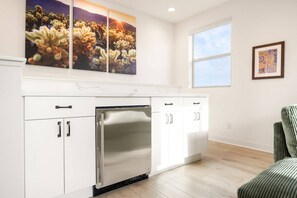 A modern kitchen with white cabinetry, a stainless steel refrigerator, and a window providing natural light.