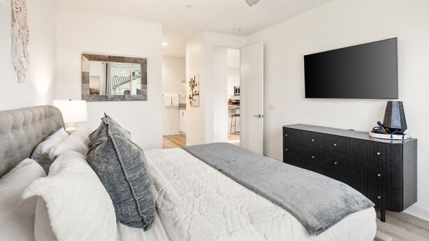 A bedroom with a bed, a dresser, a television, and a ceiling fan.