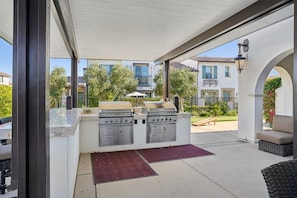 Un patio al aire libre con una parrilla, una zona de estar y vistas a casas vecinas.