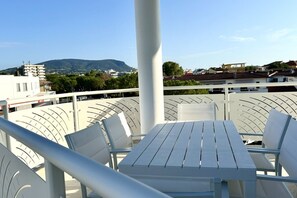 A balcony with a table and chairs, overlooking a cityscape with buildings and a mountain. - M412 - Marcelli, three-room apartment with terrace and parking space (Marcelli)