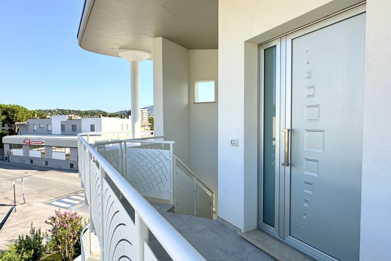 Un edificio moderno con un balcone, una porta con maniglia e cielo sereno.