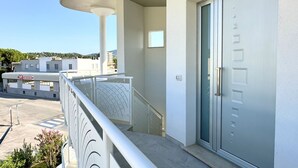 Un edifici modern amb un balcó, una porta amb vària i un cel clar.