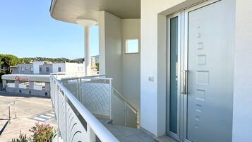 Un edificio moderno con un balcone, una porta con maniglia e cielo sereno.