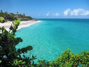 A beach with clear turquoise water, a sandy shore, and lush greenery. - Amazing Pool & 2 min walk to beach - Ocean View (Belair)