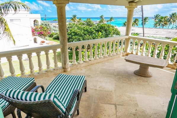 A balcony with a view of the ocean, two wicker chairs, and a stone table. - Amazing Pool & 2 min walk to beach - Ocean View (Belair)