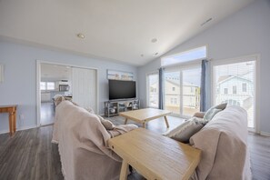 Sala de estar con sofá, mesa de centro y televisor. Hay una puerta corrediza que da a un balcón.