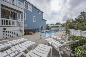 A pool area with lounge chairs, a hot tub, and a covered patio.