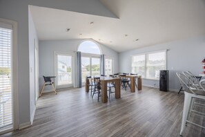 A spacious kitchen with a dining area, large windows, and a view of the outside.