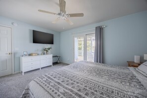 A bedroom with a bed, a dresser, a television, a ceiling fan, and a window with curtains. - 1892 - Carolina Bliss - Large Corolla Escape | Sleeps 30, Pool & Beach (Corolla)