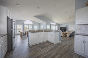 Una cocina amplia con una isla grande, piso de madera y un comedor con mesa y sillas.