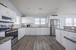 A modern kitchen with white cabinetry, a stainless steel refrigerator, and a built-in oven.