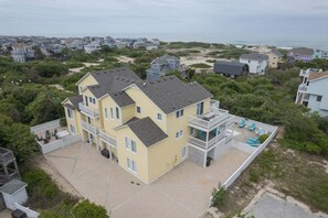 Un edificio de varios pisos con balcón, un patio con sillas y vista a la playa.