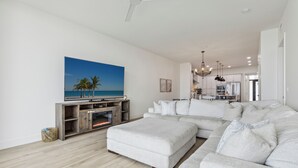 A modern living room with a sectional sofa, a flat-screen TV, and a fireplace. - Sleek Coastal Condo with Stunning Riverfront Views and Luxury Amenities (Melbourne Beach)
