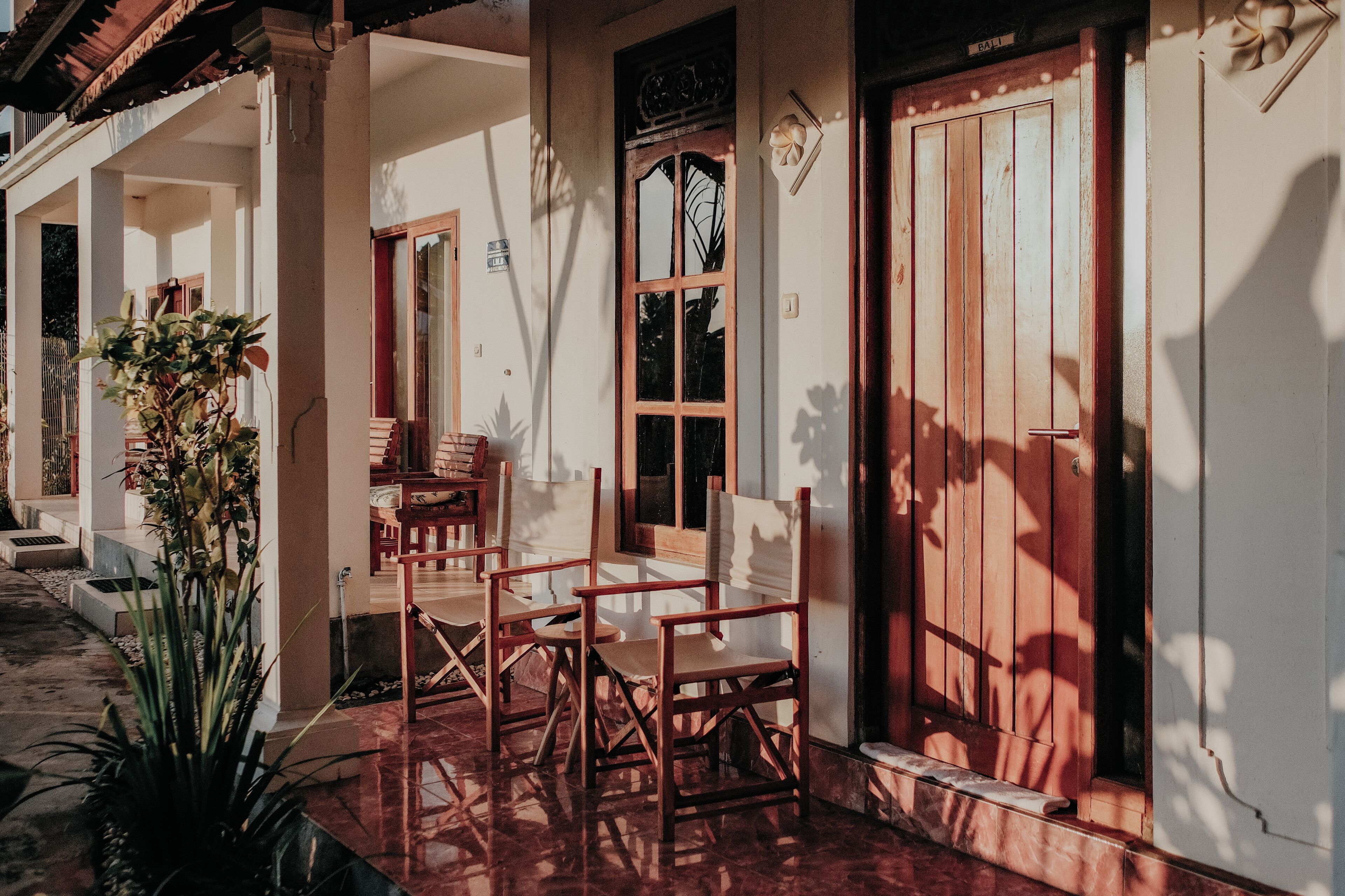 Una casa de madera tradicional con un porche, un comedor con sillas y un ventanal grande.