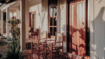 Una casa de madera tradicional con un porche, un comedor con sillas y un ventanal grande.