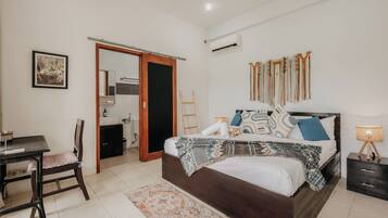 A bedroom with a bed, bedside table, chair, and a small desk.