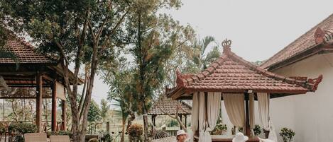 A pool area with a gazebo, lounge chairs, and a dog.