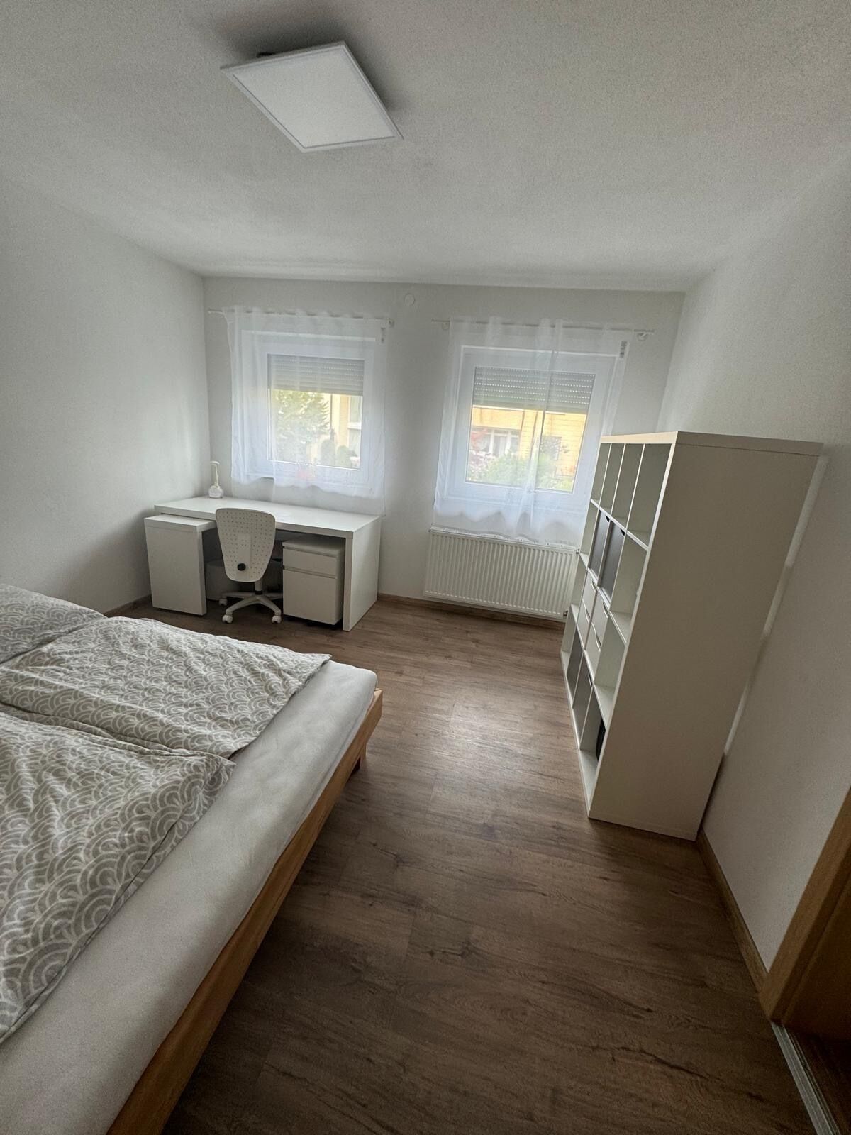 Une chambre à coucher avec un lit, un bureau et une armoire.