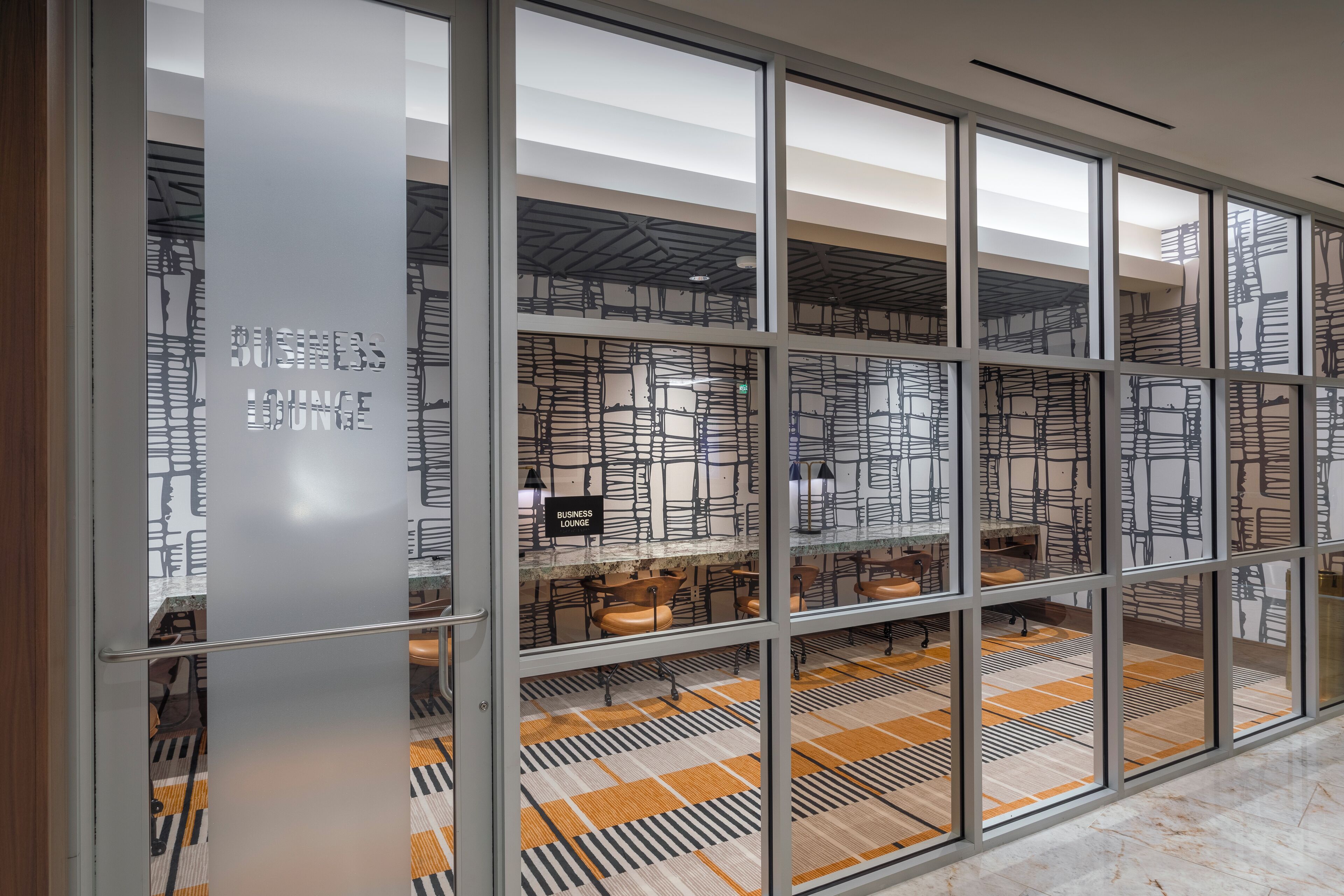 A modern interior with glass partitions, a patterned floor, and a ceiling with a geometric design.