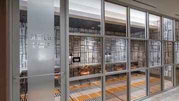 A modern interior with glass partitions, a patterned floor, and a ceiling with a geometric design.