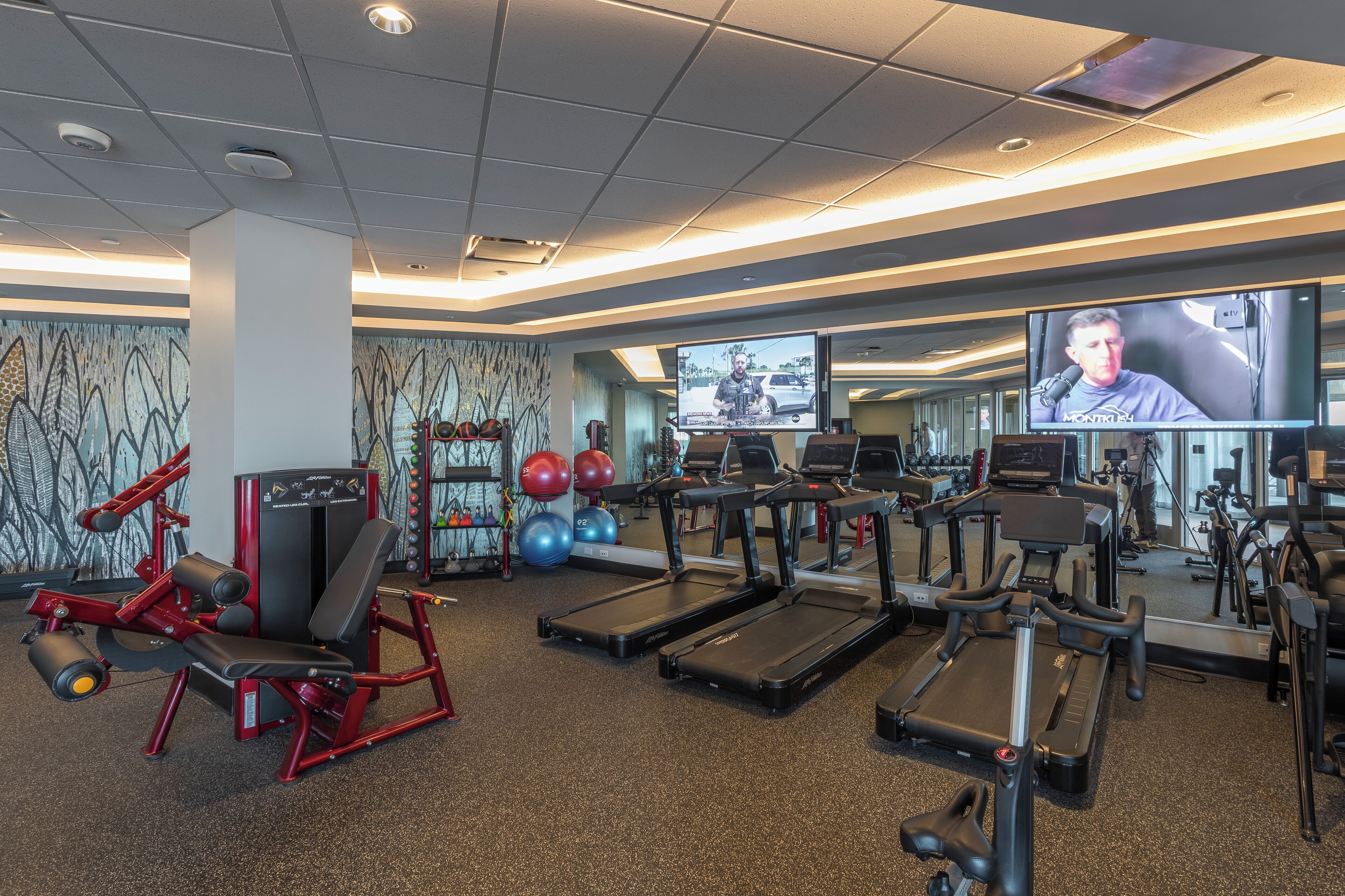 A gym with treadmills, weight machines, and exercise balls.