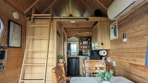 A cozy cabin interior with a wooden interior, a dining table with chairs, a ladder, a kitchenette, and a small refrigerator. - Charming Tiny House with Breath-Taking Views in Delano, TN (Delano)