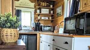A kitchen with wooden cabinets, a microwave, a coffee maker, and a sign that says "Hey Y'all Welcome". - Charming Tiny House with Breath-Taking Views in Delano, TN (Delano)