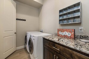 Een wasserette met een wasmachine, een droogrek en een aanrecht met een bord waarop 'FOLD' staat.