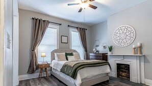 Ein Schlafzimmer mit Bett, Deckenventilator, Kamin und Wanddekoration.