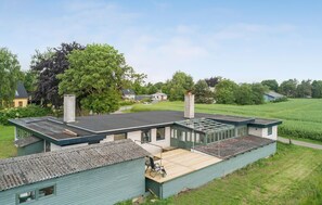 A modern house with a large deck, a chimney, and a garden. - Cozy home in Bandholm with WiFi (Bandholm)