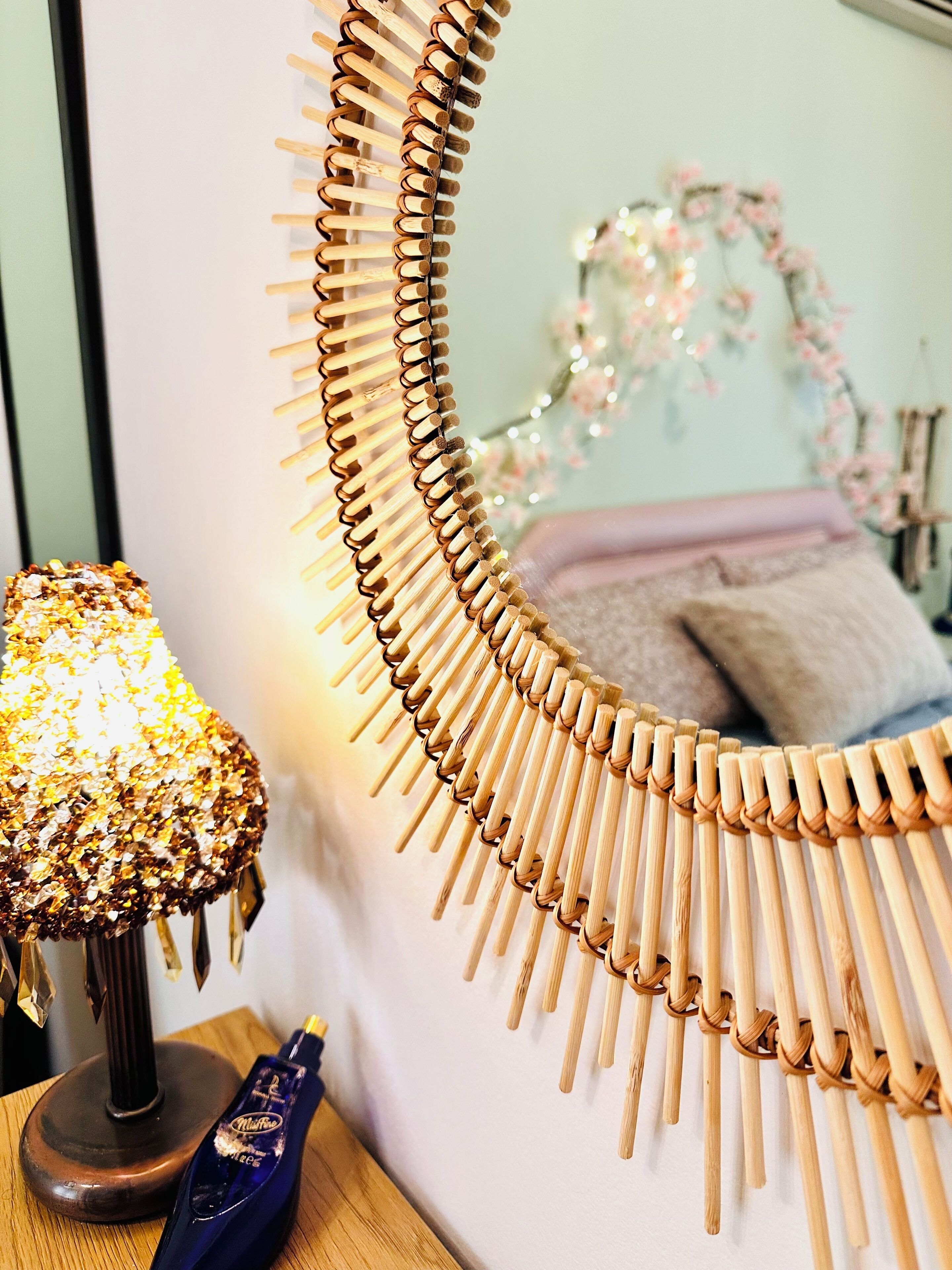 Een spiegel met houten lijst en een decoratieve lamp ernaast.