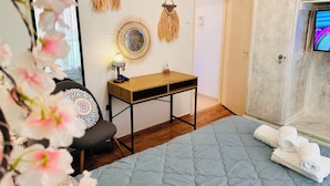 Une chambre à coucher comprenant un lit, une table de chevet, une chaise, un miroir et un téléviseur.