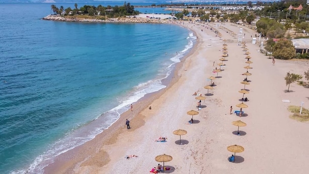 Une plage bordée de rangées de parasols et où l’on peut voir des gens se détendre.