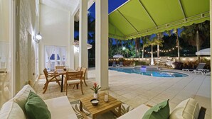 Ein überdachter Außenbereich mit Pool, Sitzgelegenheiten und Essbereich.