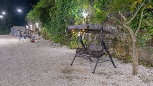 Een patio met grind, een schommelstoel, buitenmeubilair en lichtjes.
