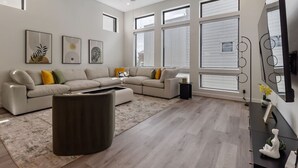 Un salon moderne avec un canapé d’angle, une table basse et un ventilateur de plafond.