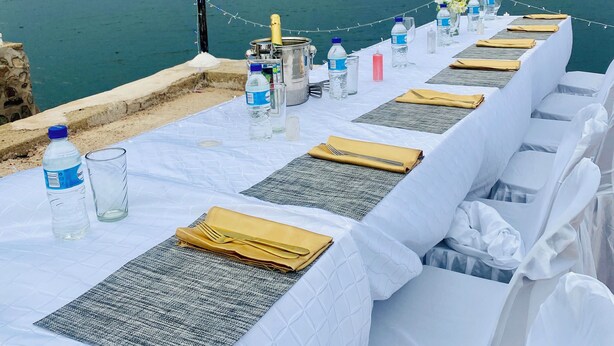 A table set for a meal with a view of the sea, a metal container, and bottled water. - BaTonga Villa (Binga)